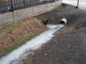 Milky white water flowing in a road side ditch.